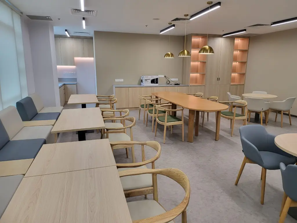 Modern office pantry with wooden furniture, warm lighting, and minimalist layout designed by a professional office renovation company.