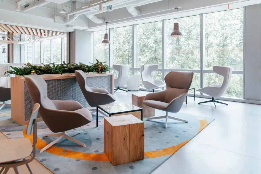 Office lounge area with comfortable chairs, lots of free space, wooden touches, and big windows