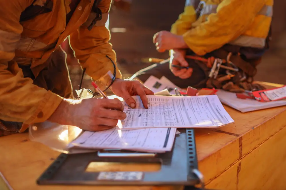 Construction workers in yellow work clothes filling out forms on site